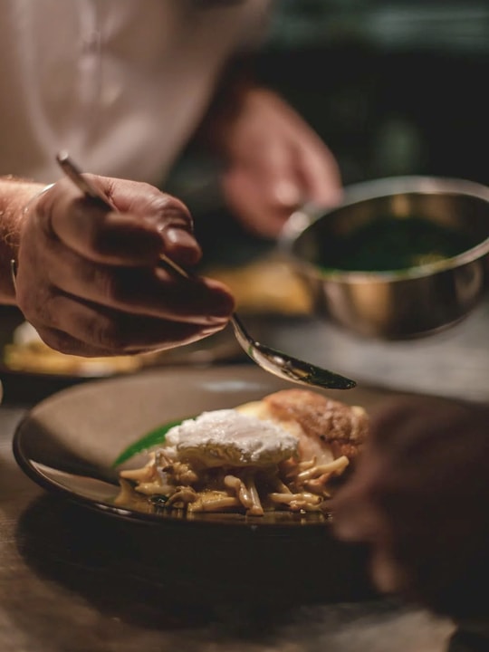 A hand pouring sauce on a dish