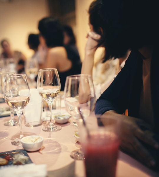 Wine glasses on the table surrounded by people