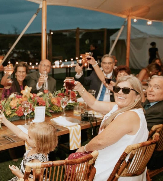 Smiling family sitting by the table raising their drinks